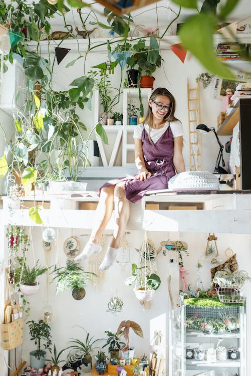 Free Young woman sitting in apartment on second level with plants Stock Photo