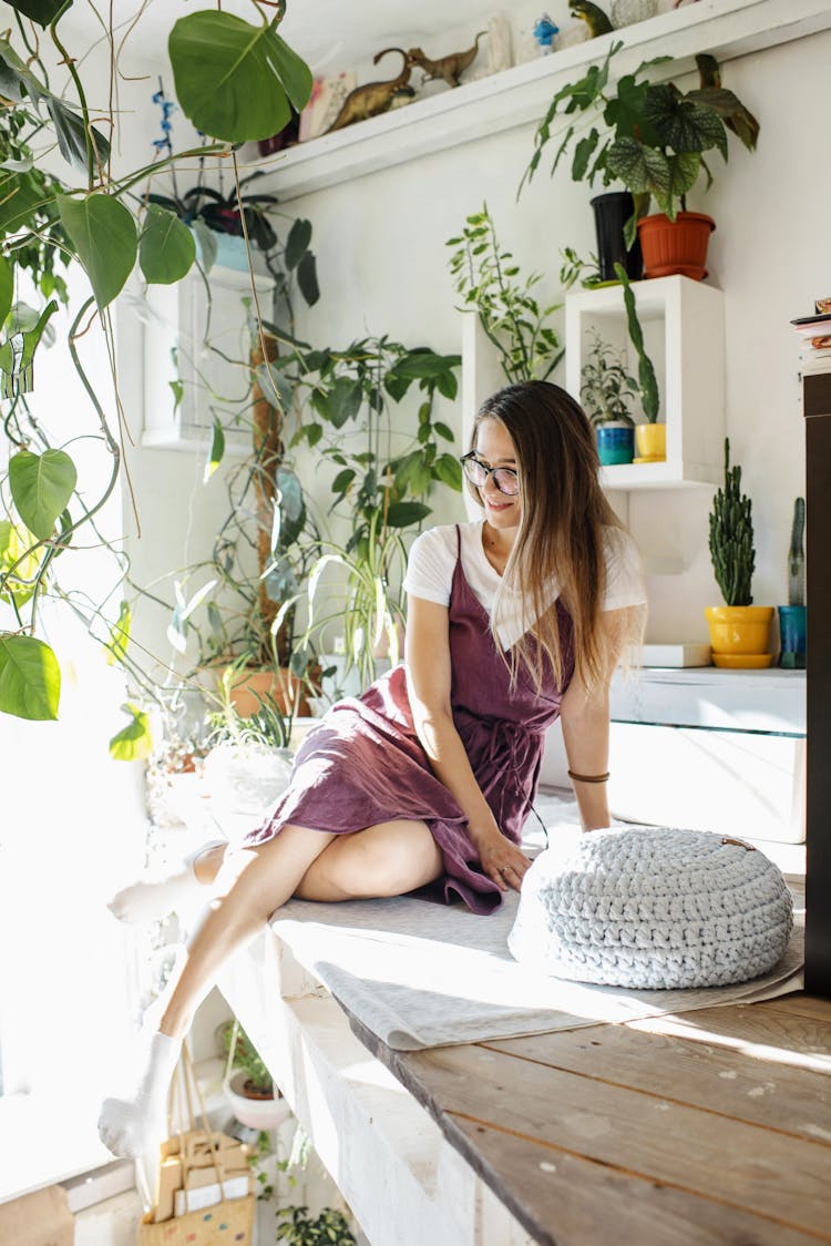 Young Woman With Plants Sitting On Second Level