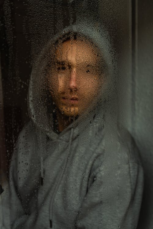 Man In Gray Hoodie Behind The Window