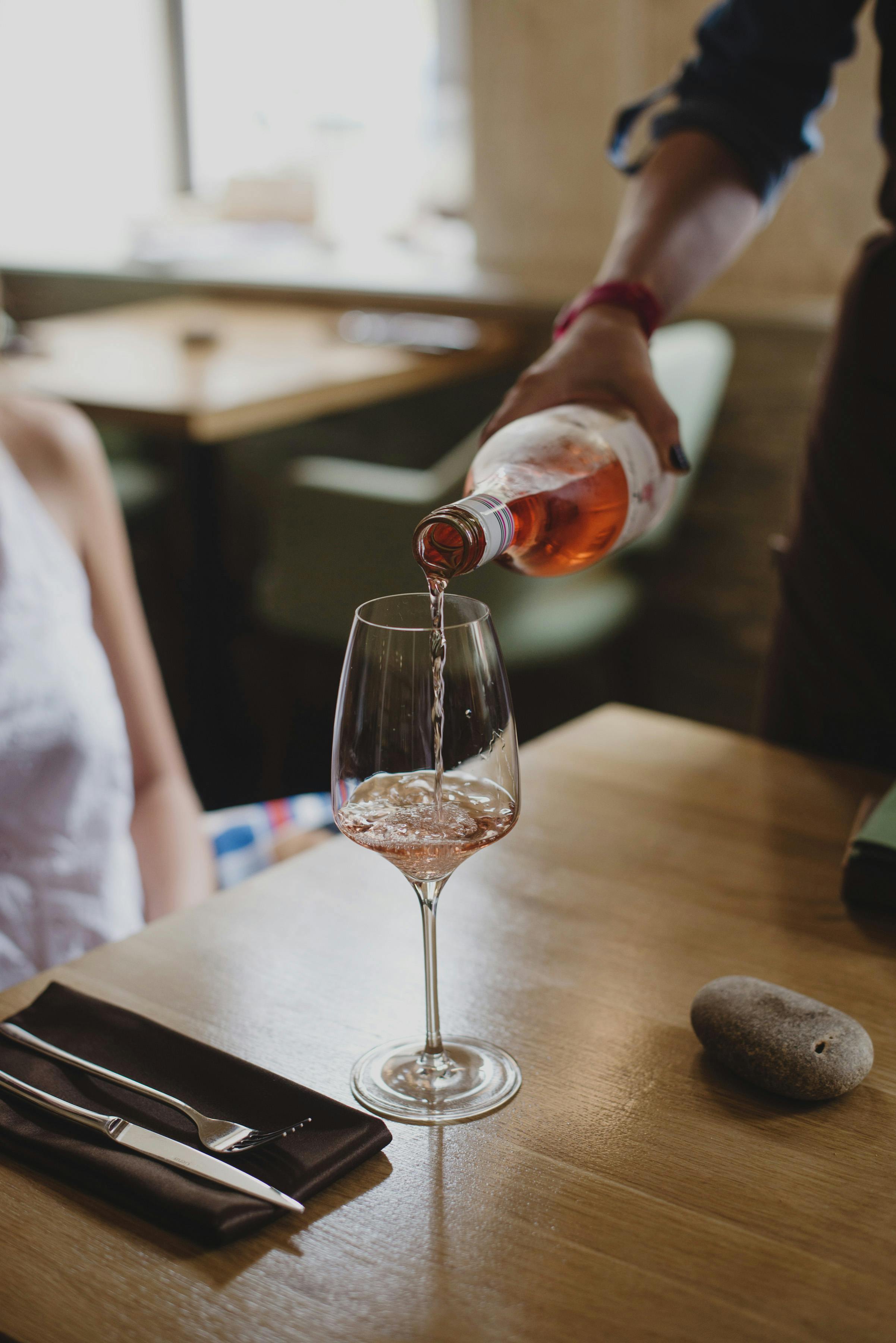 A person pours red wine into a glass, creating a romantic dining atmosphere.