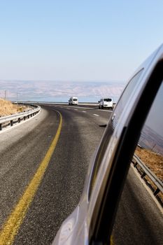View from a moving car on a scenic highway with other vehicles in motion.