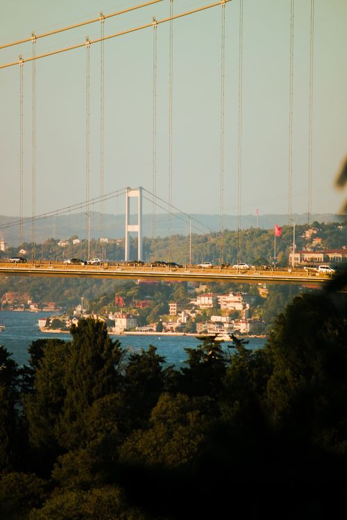 Free Scenic view of the Bosphorus Bridge in Istanbul with an urban skyline and lush greenery at sunset. Stock Photo