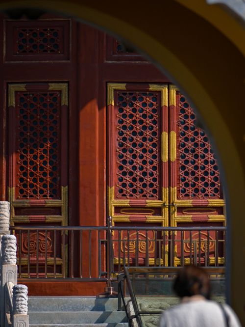 Free Red and gold ornate temple door viewed through an arch, capturing traditional Chinese architecture. Stock Photo