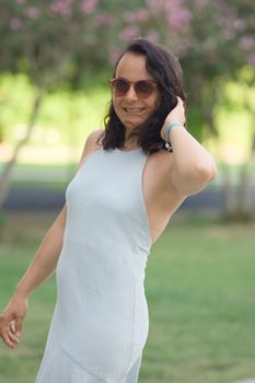 Elegant woman in a light dress posing in a vibrant garden setting in Istanbul, Turkey.