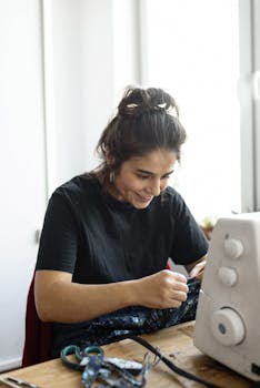 Joyful woman focused on sewing project at home workspace.
