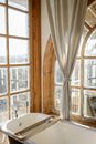 From above of bathtub in light bathroom with big shabby windows in vintage interior