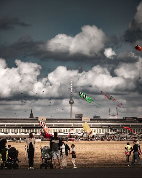 Free Families enjoy a vibrant kite festival at Tempelhofer Feld with Berlin TV Tower in the backdrop. Stock Photo