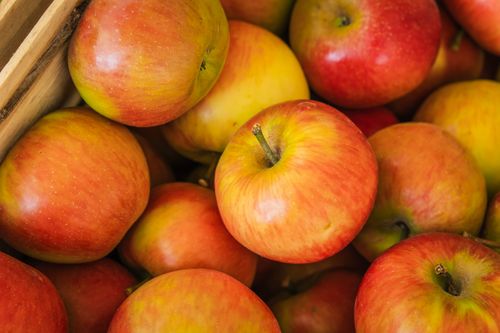 Free A vibrant close-up shot of ripe red and yellow apples in a wooden crate. Stock Photo
