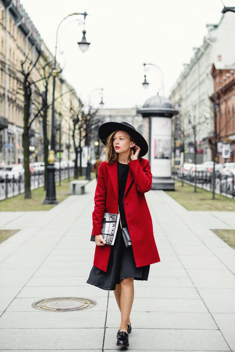 Woman In Red Coat And Black Skirt Walking On Sidewalk