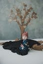 Small worried child sitting on black blanket on floor in front of decorated wall and looking at camera