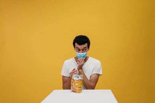 Man in White Crew Neck T-shirt Eating Chips