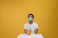 一名男子在隔离期间戴着口罩享用零食，展现了疫情下的生活方式