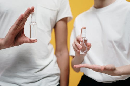 Free People in White Crew Neck T-shirt Holding Clear Spray Bottles Stock Photo