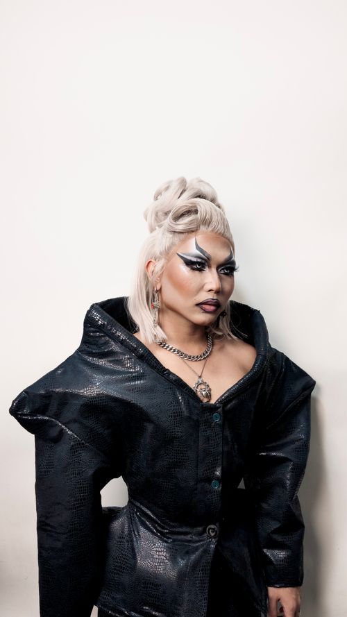 Free Stylish woman wearing an avant-garde black jacket and statement makeup, exuding confidence. Stock Photo