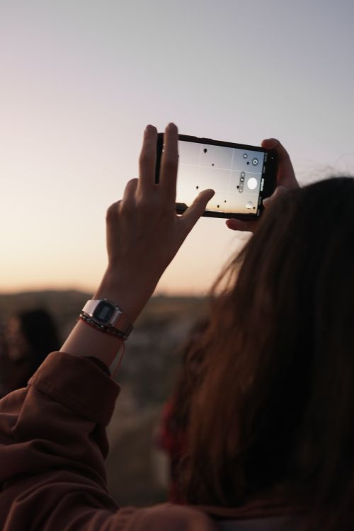 Free Silhouette of a person photographing a scenic sunset with a smartphone in Türkiye. Stock Photo