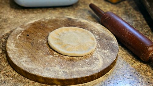 Free Freshly prepared bread dough resting on a floured wooden board next to a rolling pin. Stock Photo