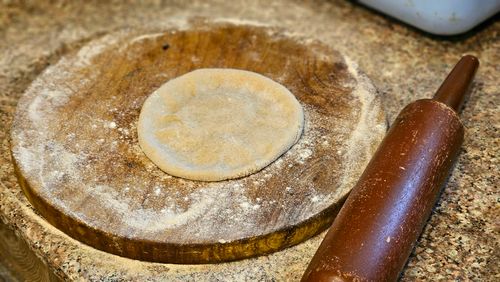 Free Detailed view of dough on a floured wooden board next to a rolling pin. Stock Photo
