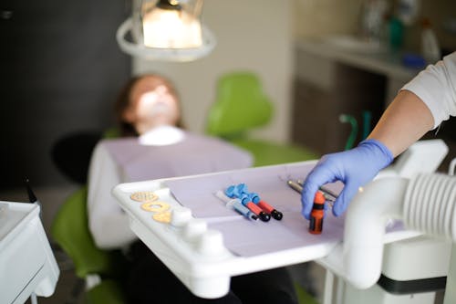 Free Crop dentist in blue rubber medical gloves curing teeth to patient in modern hospital office Stock Photo