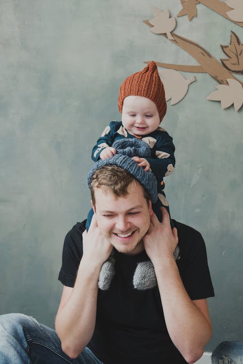 A Smiling Man Carrying his Child on the Shoulders