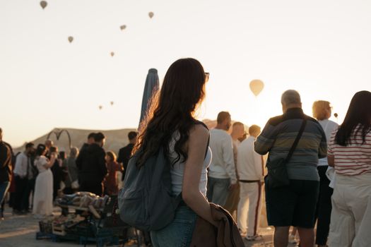 Crowd watching hot air balloons at sunrise in Cappadocia, Türkiye.