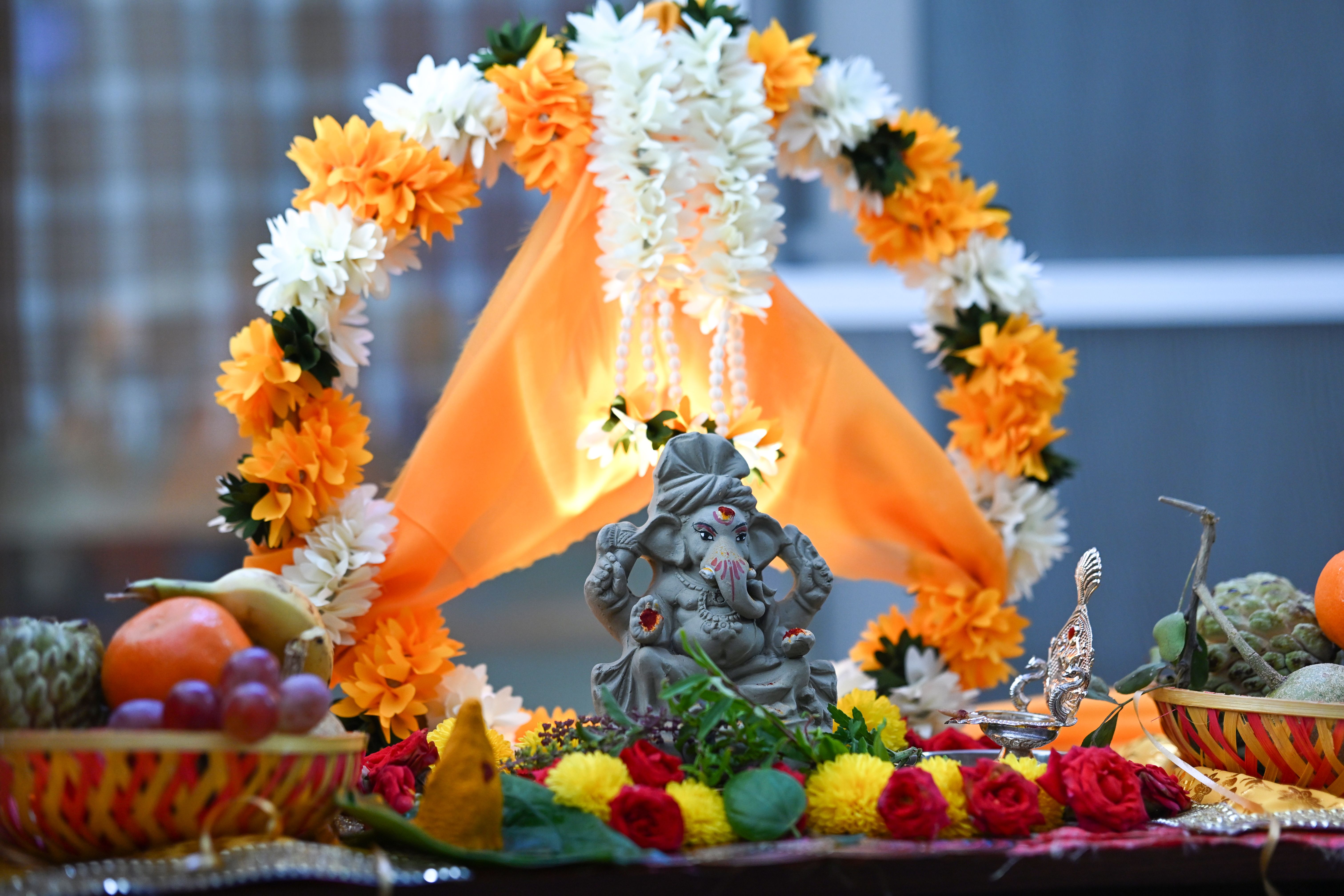 Decorative Ganesha idol with vibrant flowers and fruits during a traditional Indian festival in Bengaluru, India.