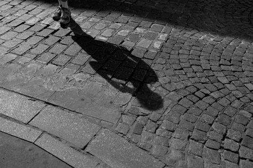 Free Artistic black and white photo capturing a silhouette on cobblestone pavement. Stock Photo