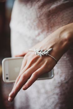 Close-up image of a woman's hand wearing a bracelet while holding a smartphone. Stylish and modern.