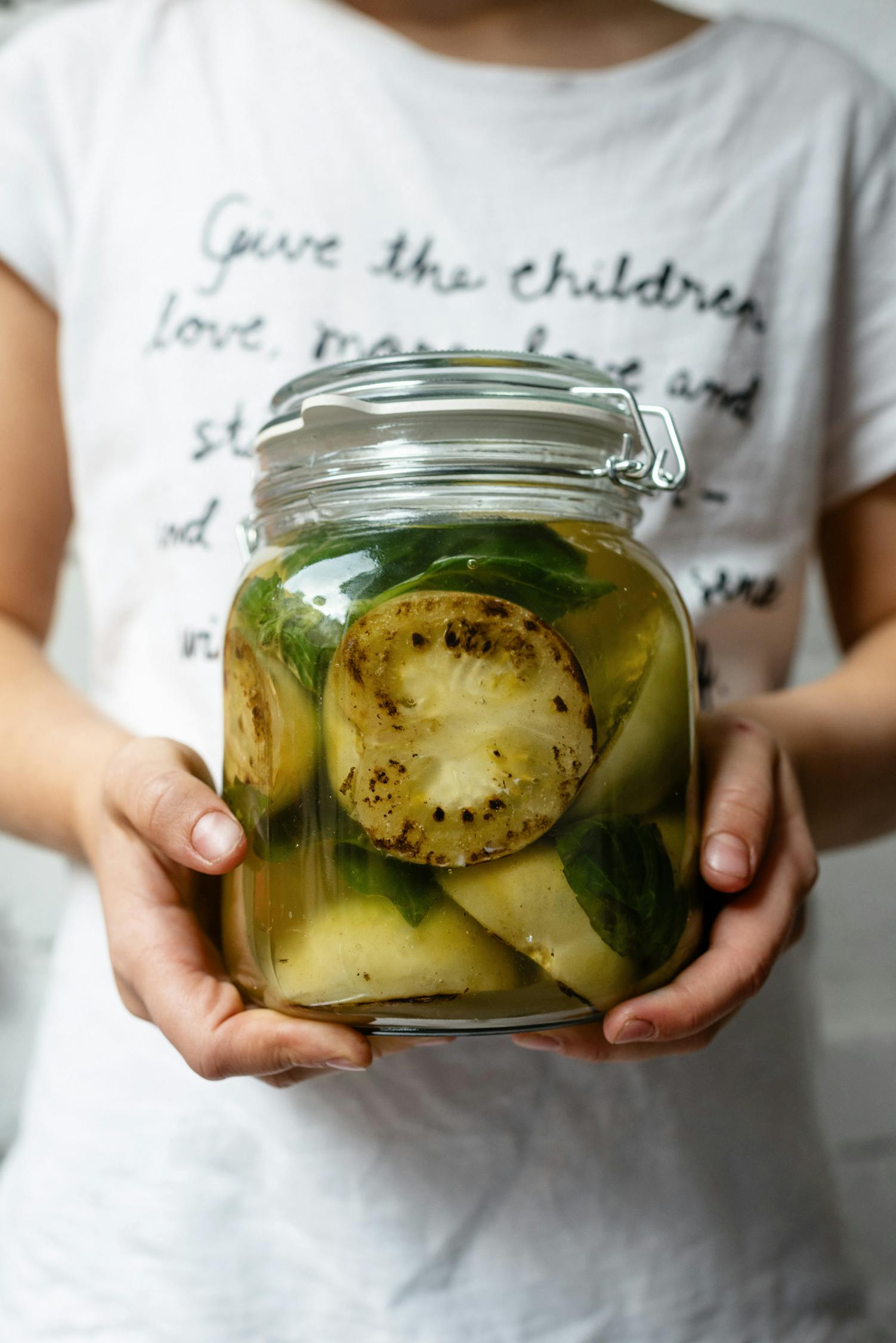 Crop unrecognizable person with jar of pickled zucchini