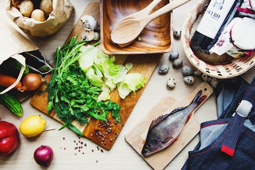 Fresh vegetables and fish on cutting board in kitchen