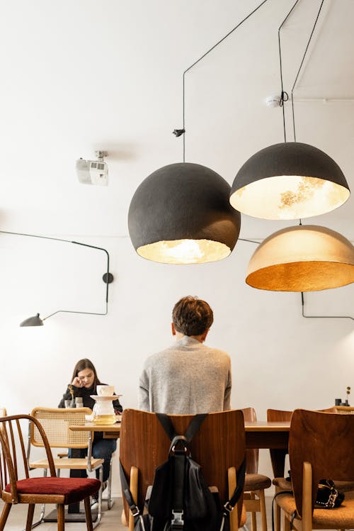 Unrecognizable male sitting in cafe in front of thoughtful teenager