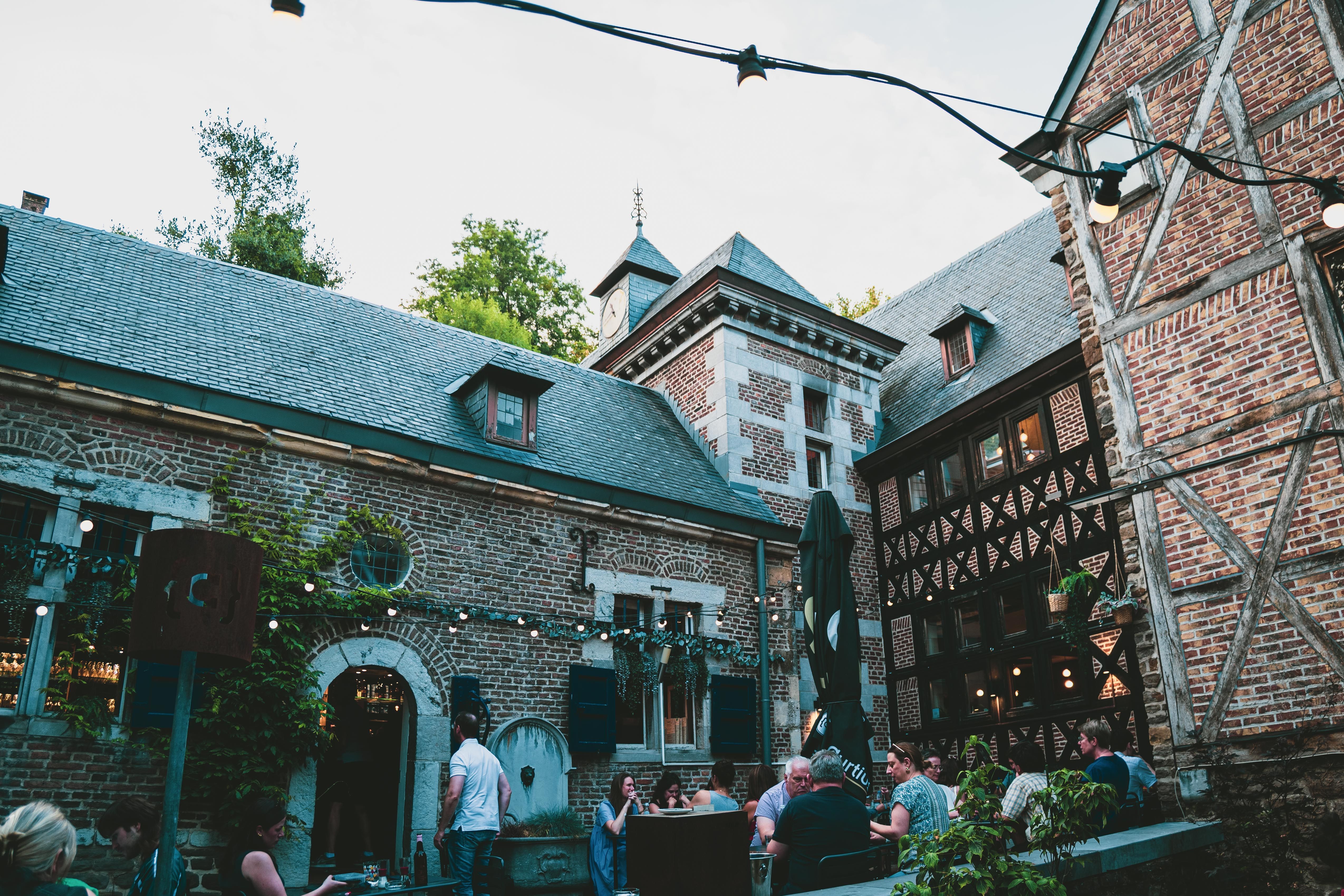 Outdoor cafe ambiance in the historic district of Stavelot, Belgium with people enjoying a cozy evening under string lights.
