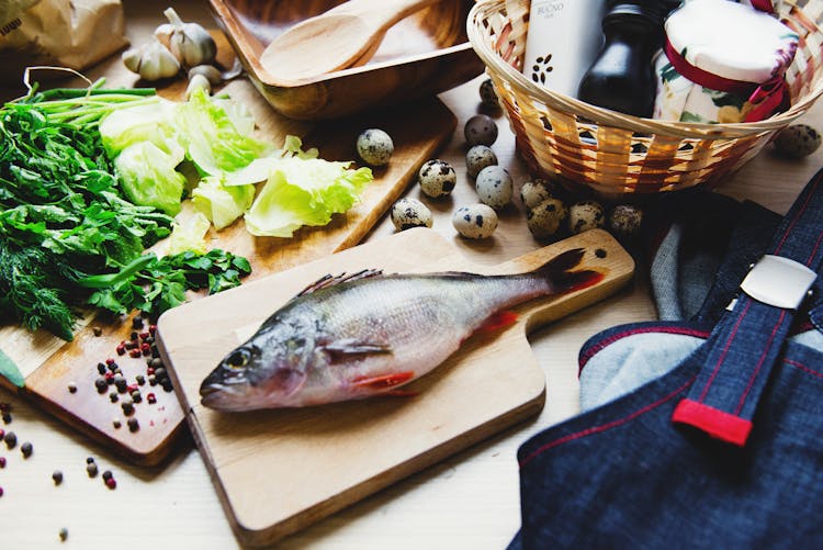 Raw Fish On Cutting Board With Lettuce In Kitchen