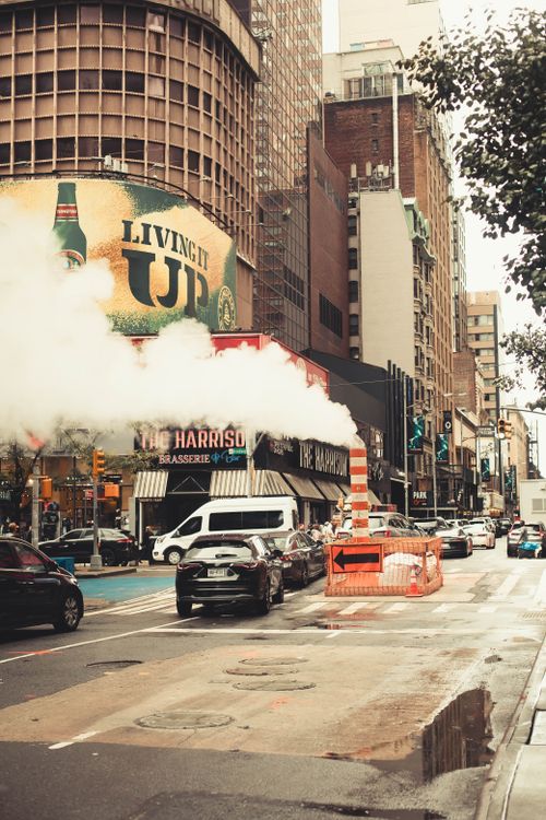 Free A bustling urban scene with steam rising and iconic New York City taxis. Stock Photo