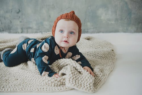 Baby  In Blue Onesie Lying On White Textile
