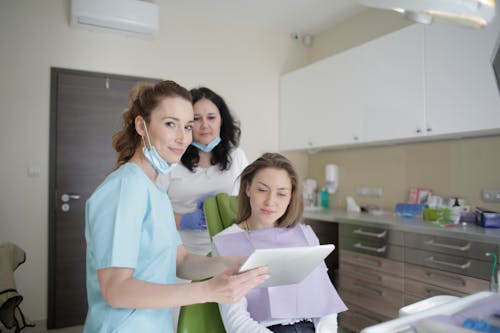 Cheerful stomatologist and assistant showing medical report to patient