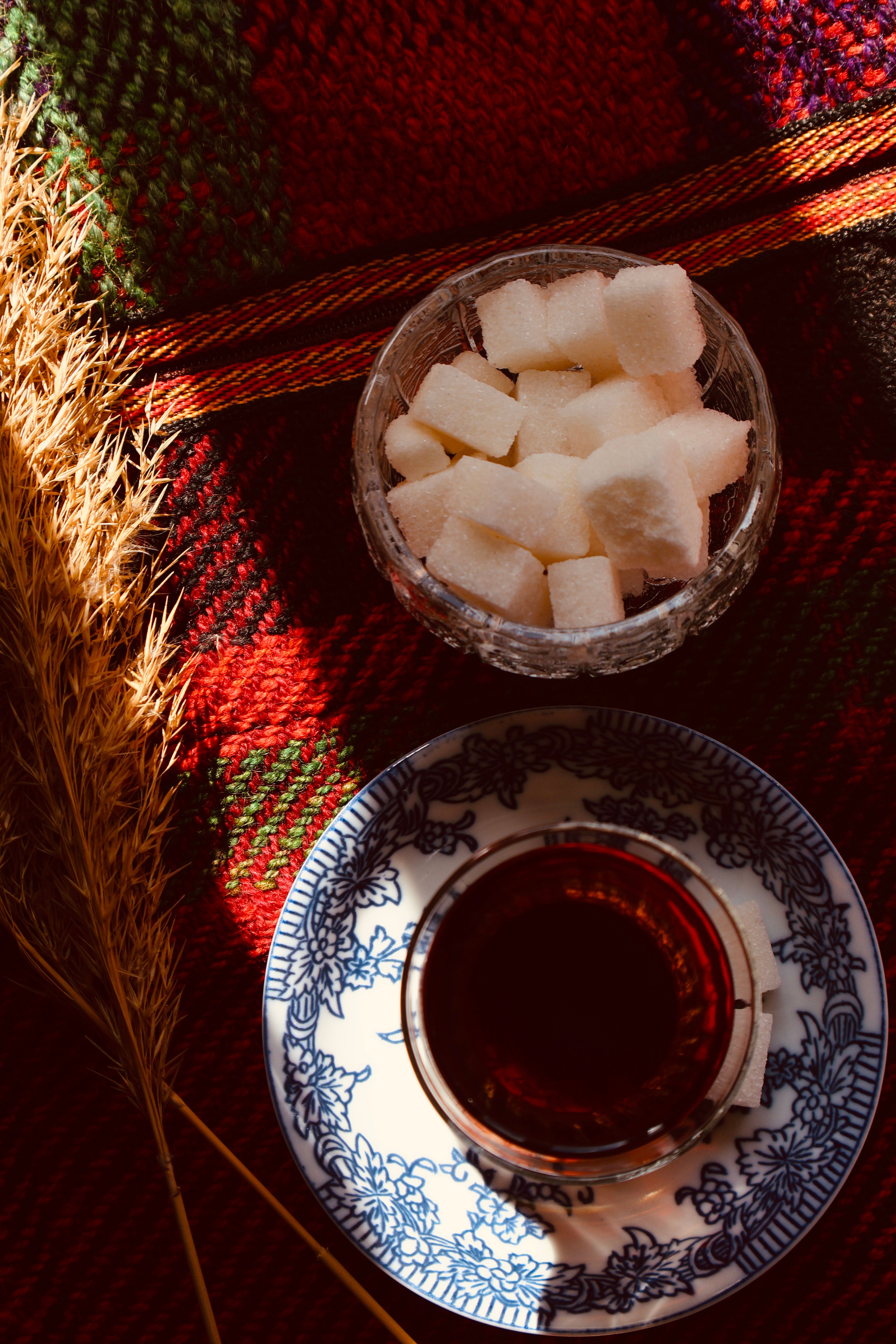 A cozy, rustic tea arrangement with sugar cubes and an elegant saucer on a vibrant textile.