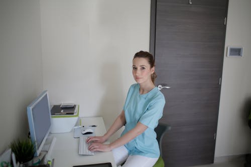 Free Woman In Blue Scrub Suit Using The Computer Stock Photo