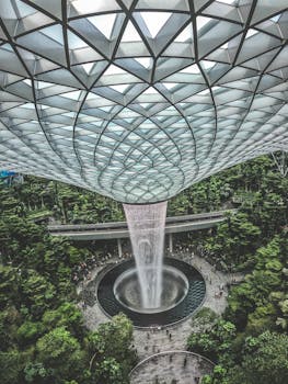Spectacular indoor waterfall amidst lush greenery and modern design in Jewel Changi Airport, Singapore.