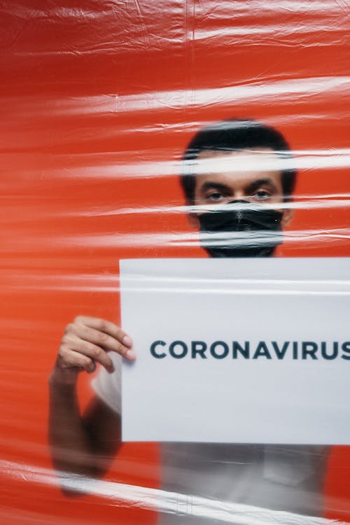 Man Behind A Plastic Holding A Poster With Concept Of Coronavirus