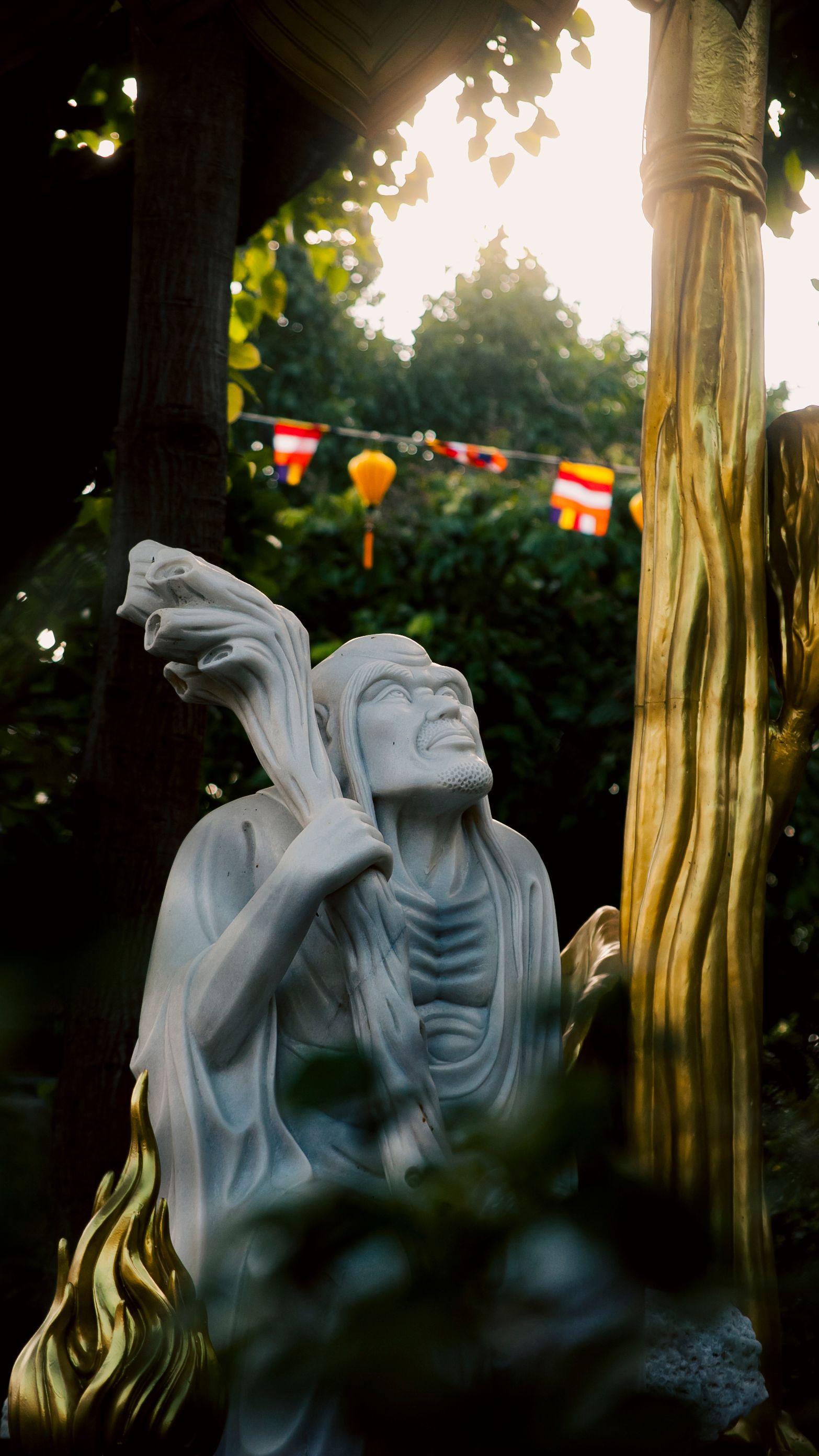 Statue in a Ho Chi Minh City garden with vibrant greenery and cultural flags.