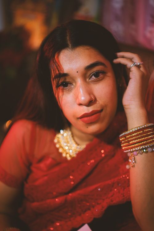 Free A thoughtful woman adorned in a beautiful red sari and traditional jewelry. Stock Photo