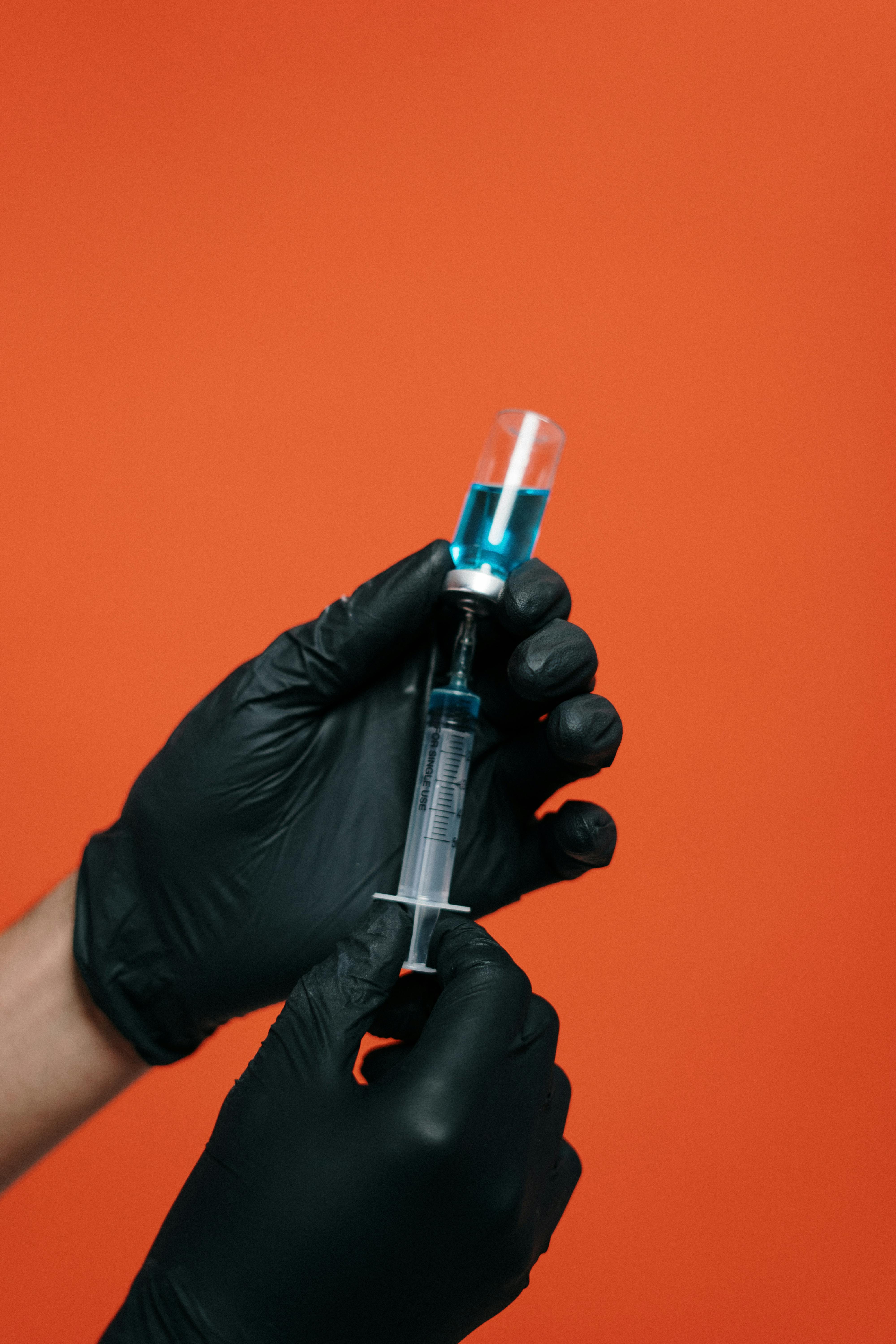 person holding a vaccine with black gloves