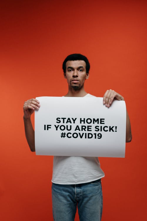 Free Man in White Crew Neck T-shirt Holding Stay At Home Sign Stock Photo