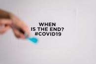 特写镜头中，一只手拿着画笔，墙上是大流行的迹象