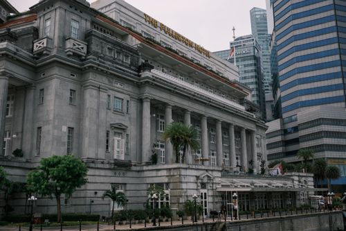 Free Classic architecture of The Fullerton Hotel amidst modern skyscrapers in Singapore's bustling business district. Stock Photo
