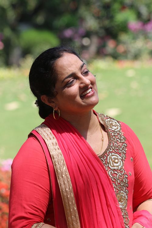 Free Joyful woman in traditional Indian dress smiling in a sunny garden setting. Stock Photo