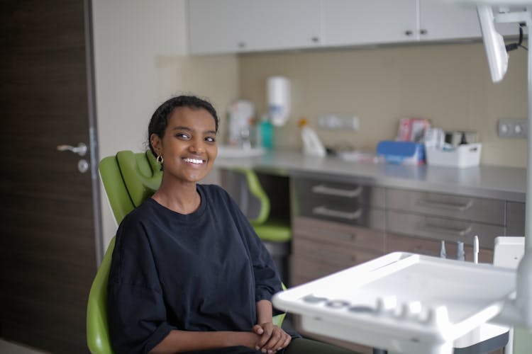 Cheerful African American Woman Sitting On Dental Chair In Clinic