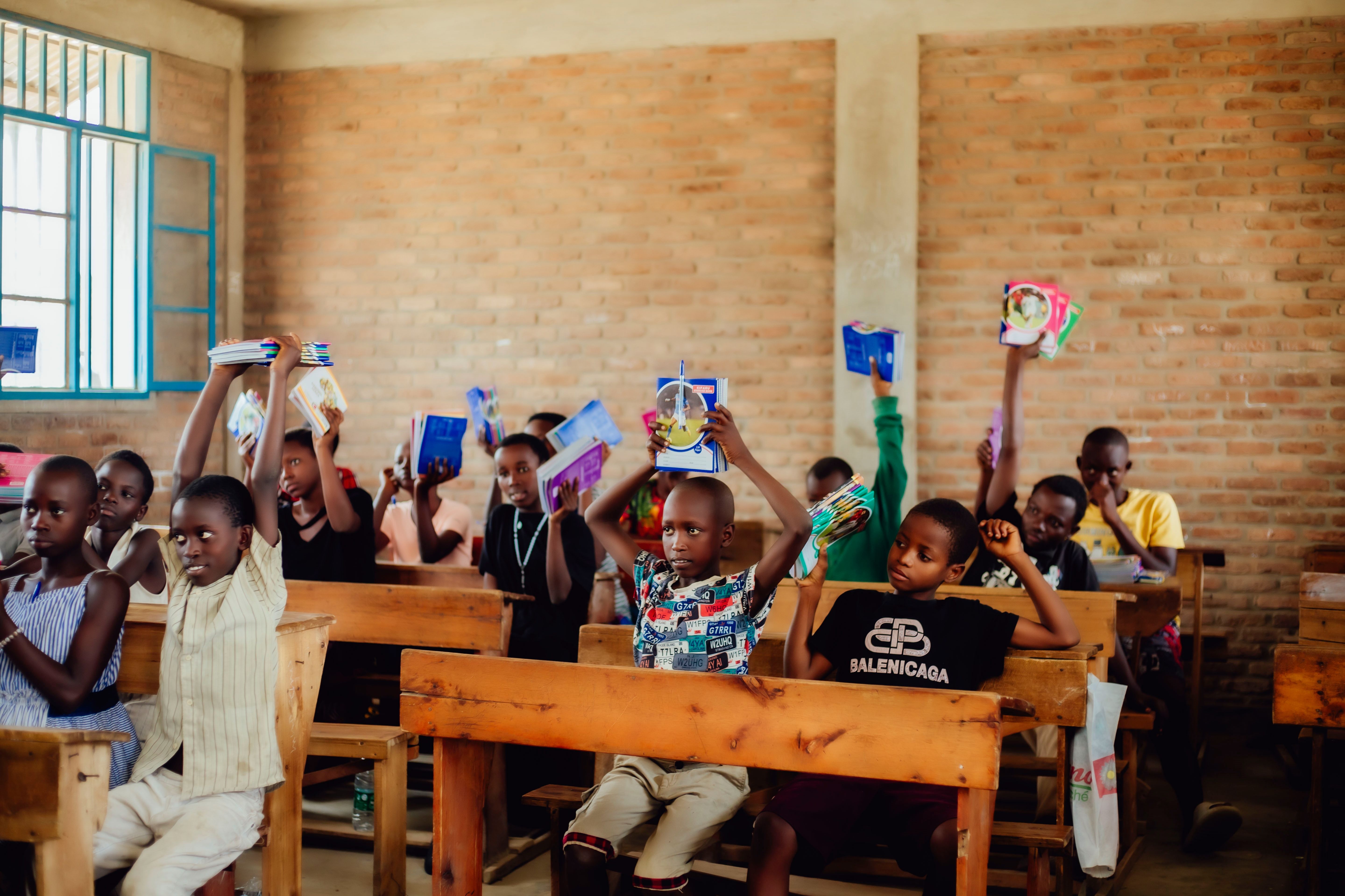Children holding school supplies in a classroom