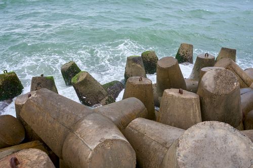 Free Concrete wave breakers on Phan Thiet coast protect against erosion, with sea waves crashing. Stock Photo