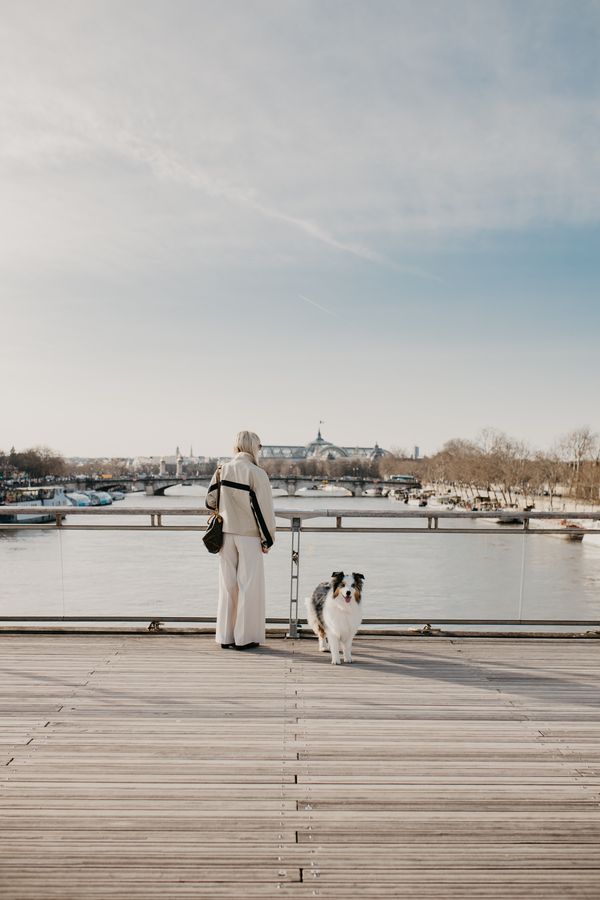 A serene moment on Pont des Arts, Paris, with a person and a dog enjoying the river view.